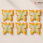 Butterfly-shaped cookies with orange and yellow accents on a beige background, branded 'Bakeyy'.