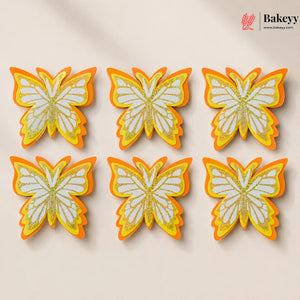 Butterfly-shaped cookies with orange and yellow accents on a beige background, branded 'Bakeyy'.