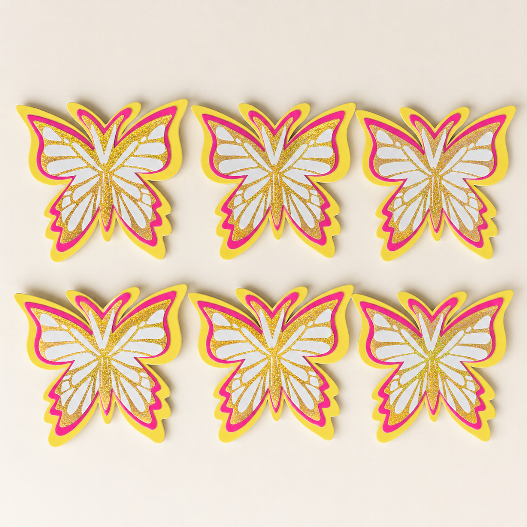 Set of six butterfly-shaped decorations with pink, yellow, and white colors on a beige background.