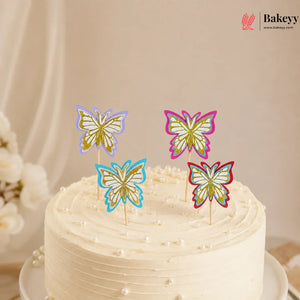 White cake with colorful butterfly cake toppers on a neutral background, featuring the brand 'Bakeyy'.