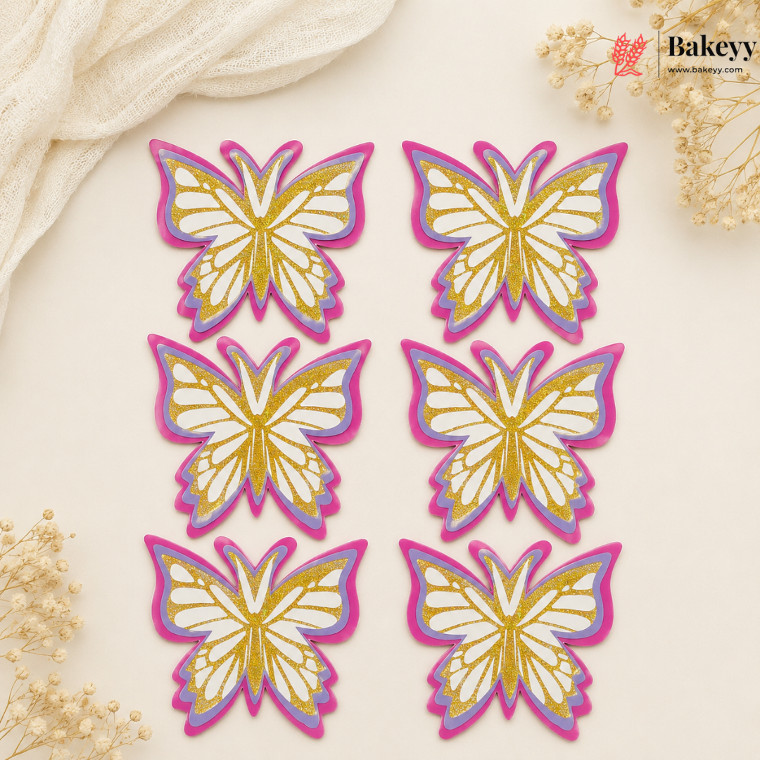 Set of butterfly-shaped decorations with gold and pink outlines on a beige background, featuring the brand 'Bakeyy'.
