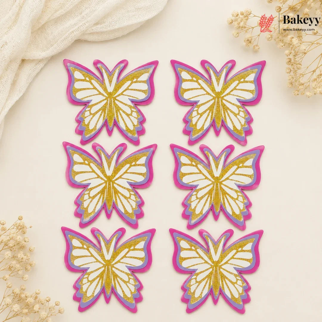 Set of butterfly-shaped decorations with gold and pink outlines on a beige background, featuring the brand 'Bakeyy'.