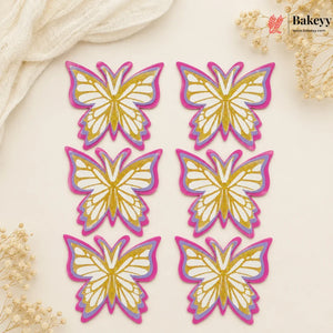 Set of butterfly-shaped decorations with gold and pink outlines on a beige background, featuring the brand 'Bakeyy'.