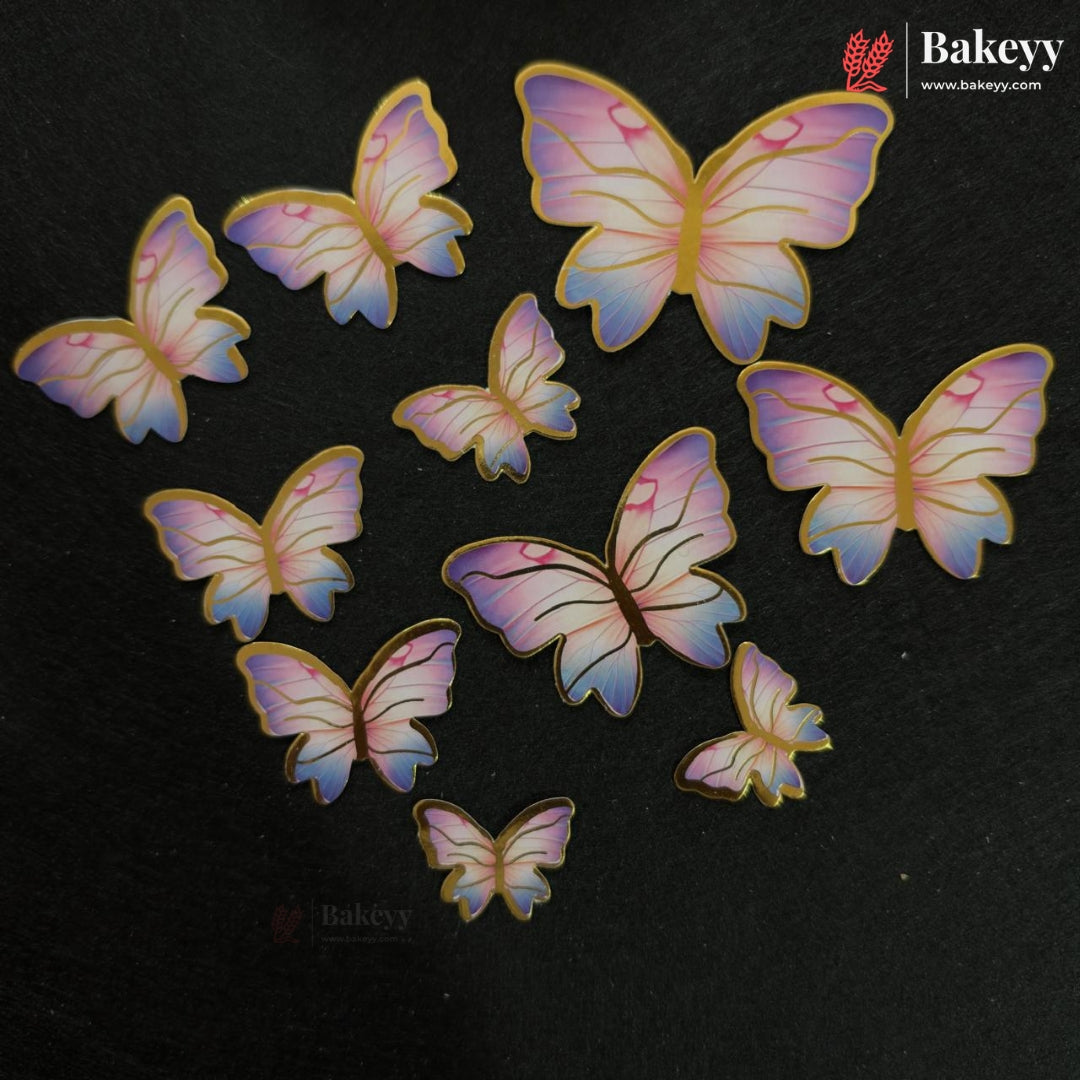 Nine butterfly-shaped cake toppers in pastel pink, purple, and blue with gold outlines, arranged on a dark textured background. The Bakeyy brand logo is visible in the top right corner.