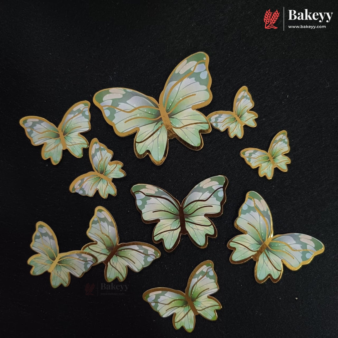 A set of butterfly-shaped decorative pieces with pale green and white marbled wings outlined in gold, arranged on a dark textured background. The Bakeyy brand logo is visible in the top right corner.