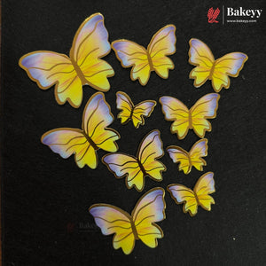 A set of butterfly-shaped decorative embellishments in yellow and purple, arranged on a black textured background. The Bakeyy brand logo is visible in the top right corner.