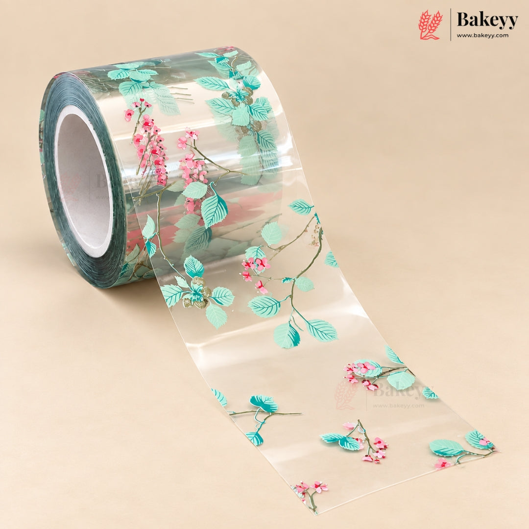 A roll of clear decorative tape with a printed pattern of mint green leaves and pink blossoms on a beige background. The Bakeyy brand logo is visible in the top right corner.