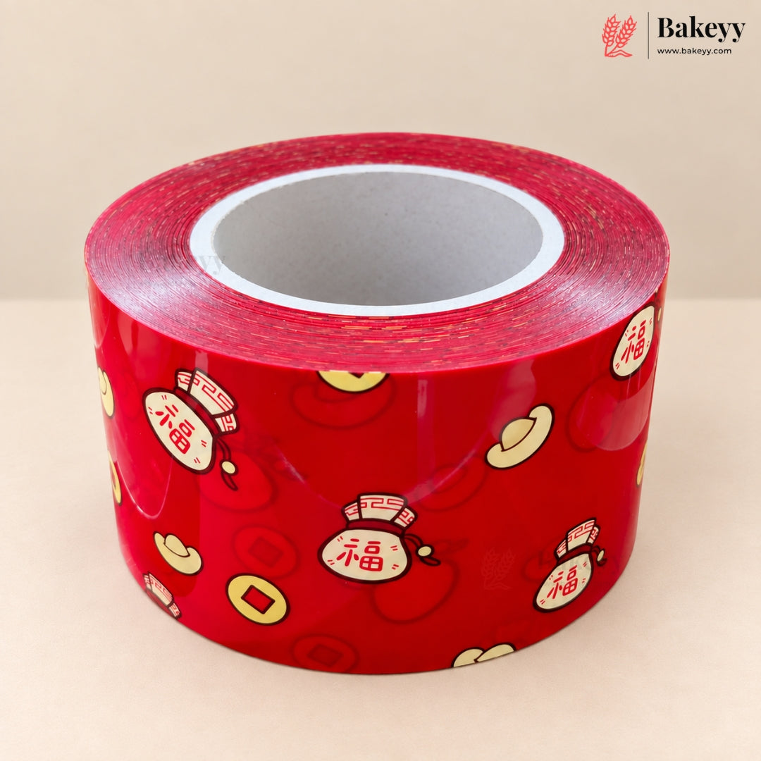 A roll of red decorative tape featuring traditional Chinese motifs including gold Chinese coins, red envelopes with Chinese characters, and a small straw hat, photographed on a neutral beige background.