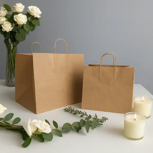 Brown paper cake bags for gift packaging on a table with candles and white roses, Bakeyy.