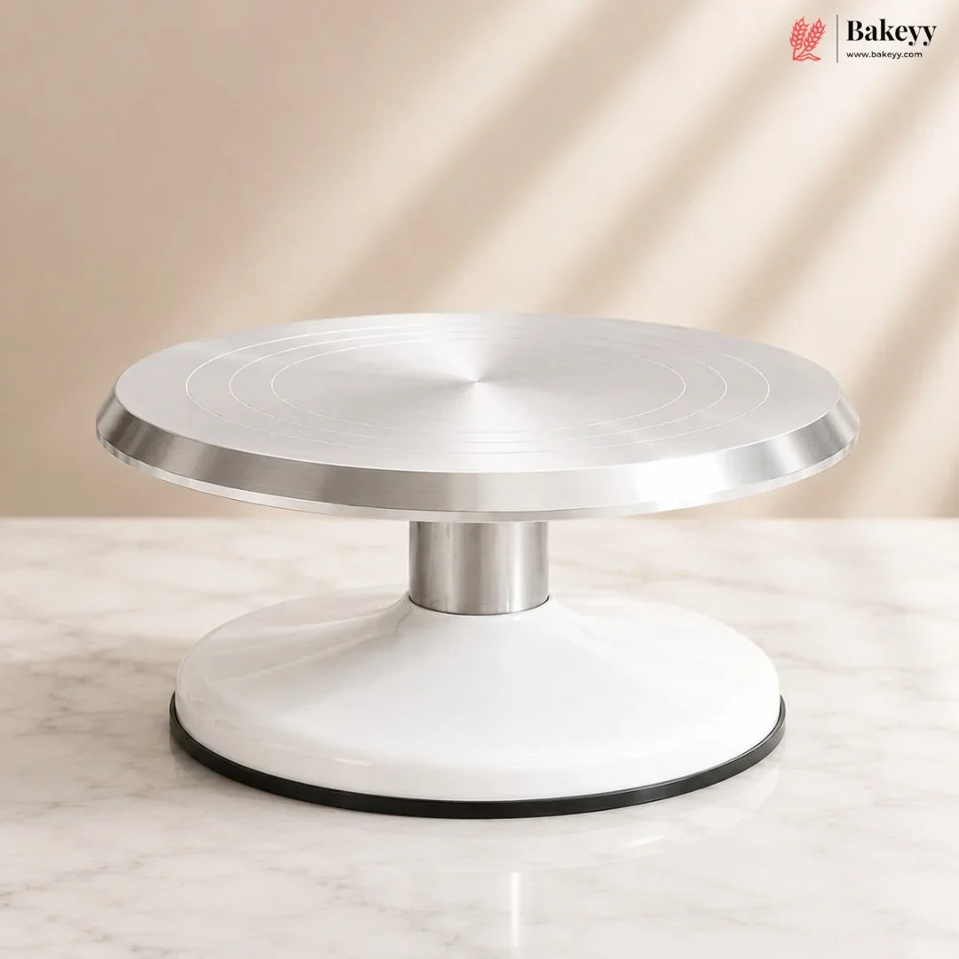 Cake turntable with metallic top and white base on a neutral background