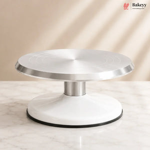 Cake turntable with metallic top and white base on a neutral background