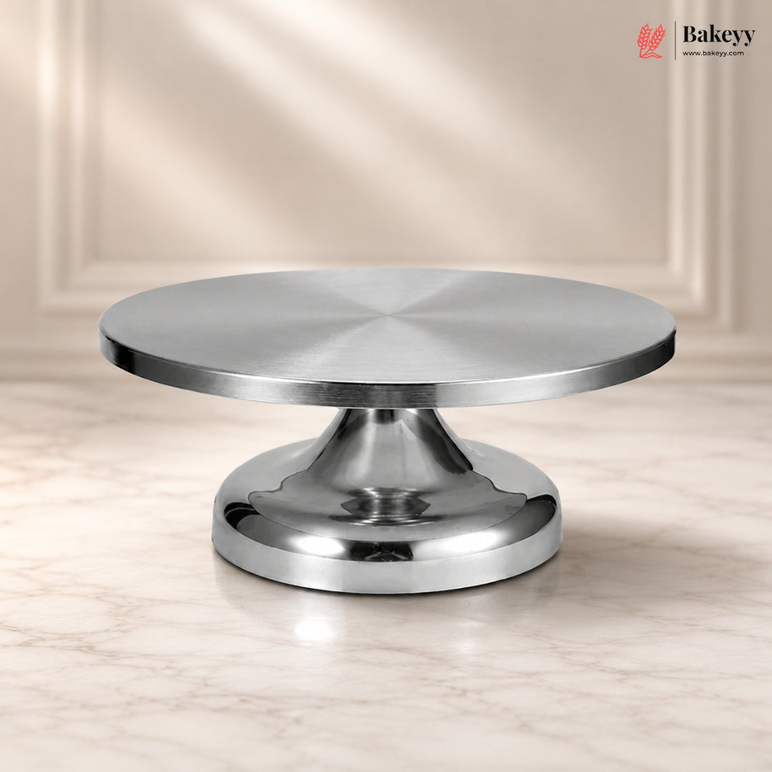 Metallic cake stand on a beige background with 'Bakeyy' branding.