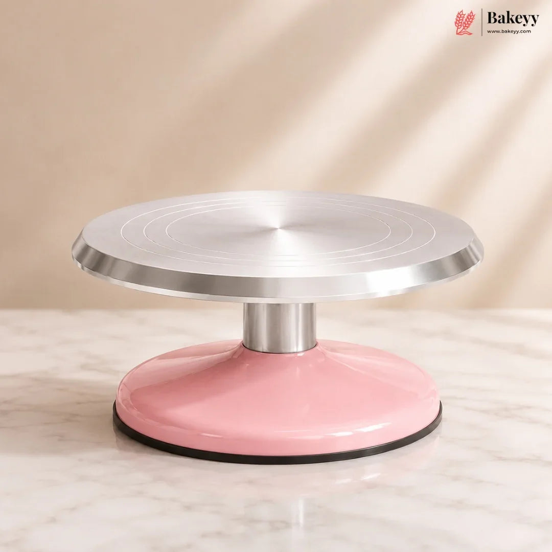 Pink and silver cake turntable on a beige background with 'Bakeyy' branding.