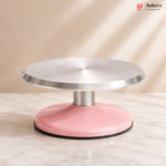 Pink and silver cake turntable on a beige background with 'Bakeyy' branding.