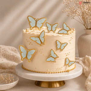 Cake with butterfly decorations on a marble stand, with a vase and decorative elements in the background.