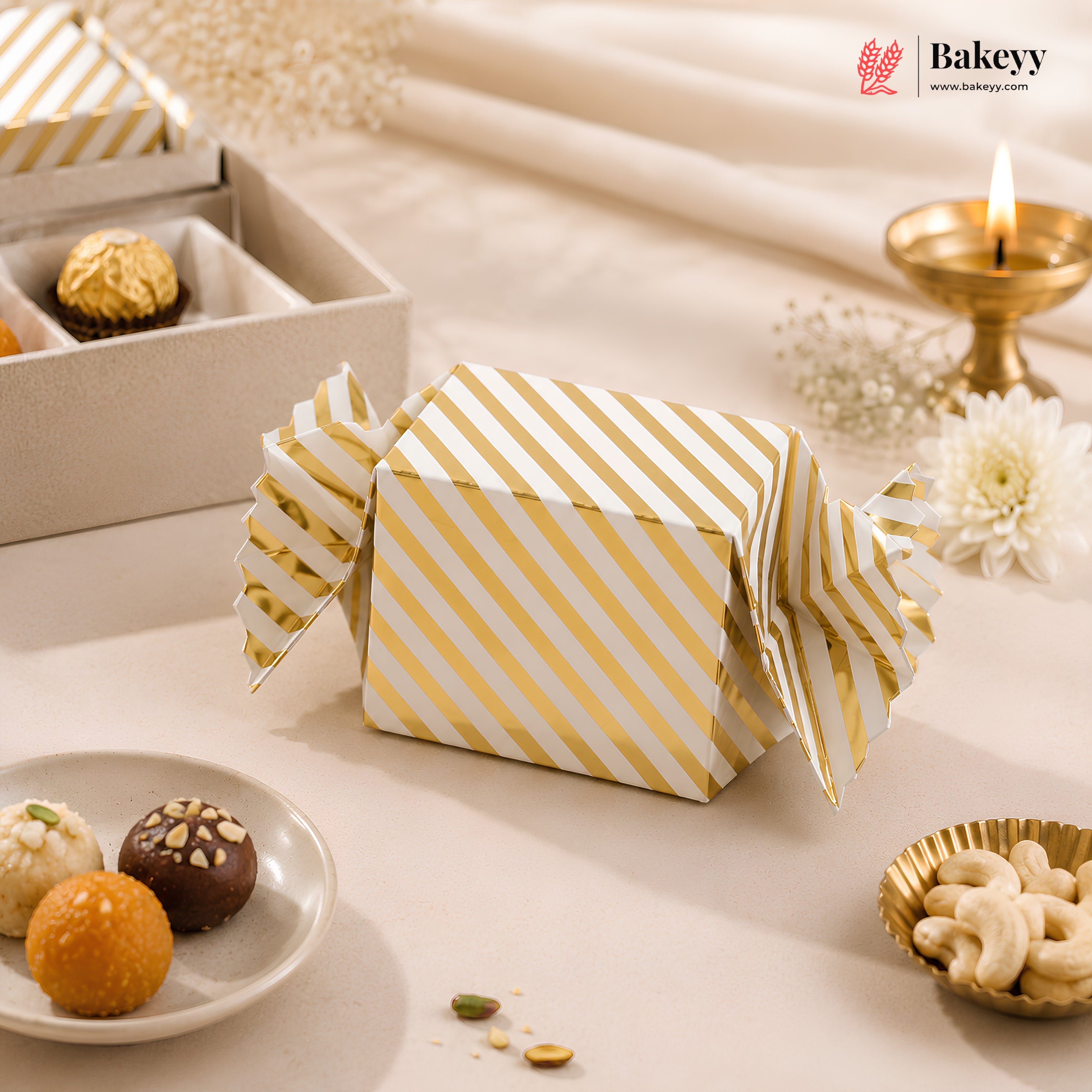 Gold and white striped gift box on a decorative table with snacks and a candle.