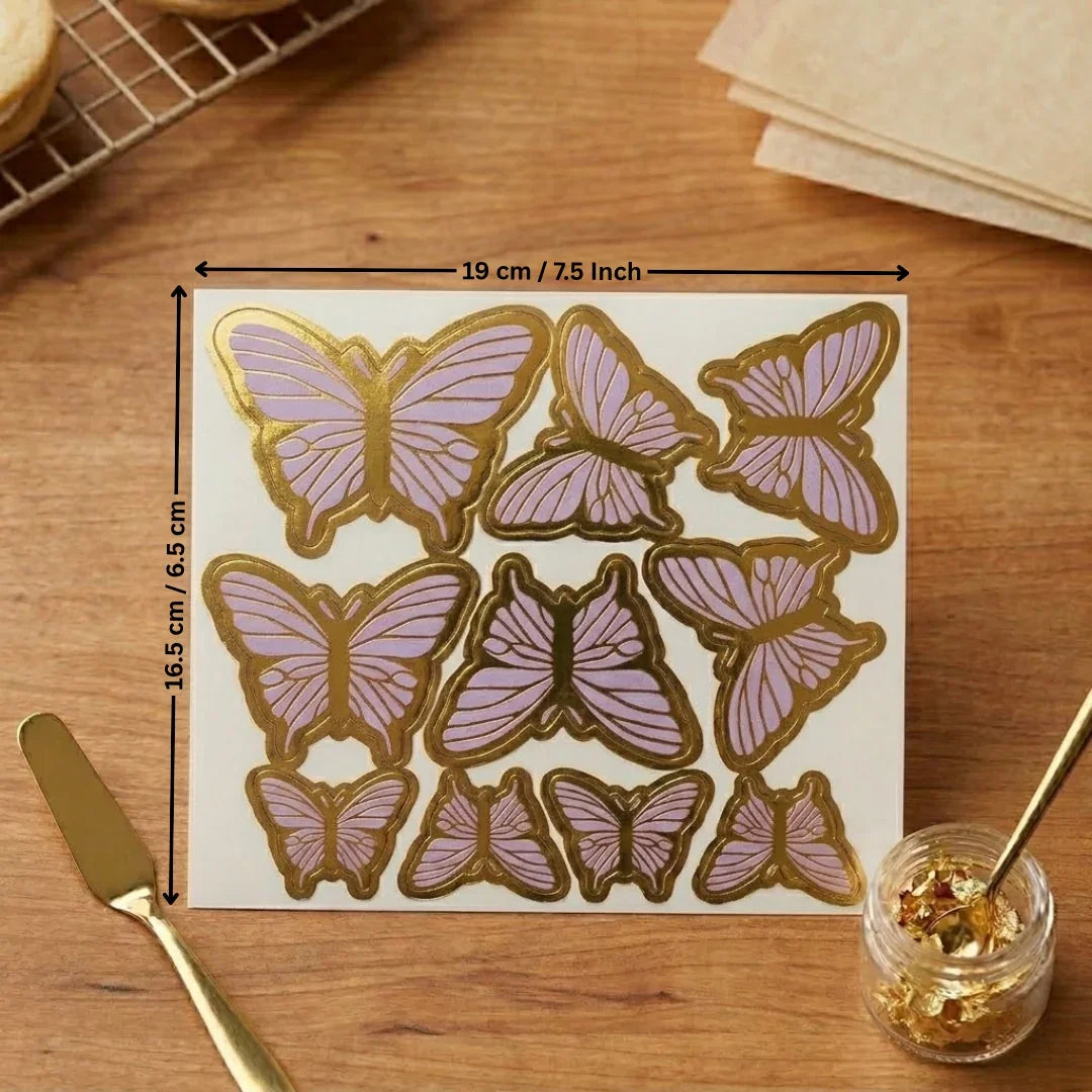 Sheet of butterfly-shaped cookies with gold and pink icing on a wooden surface, with measurements indicated.