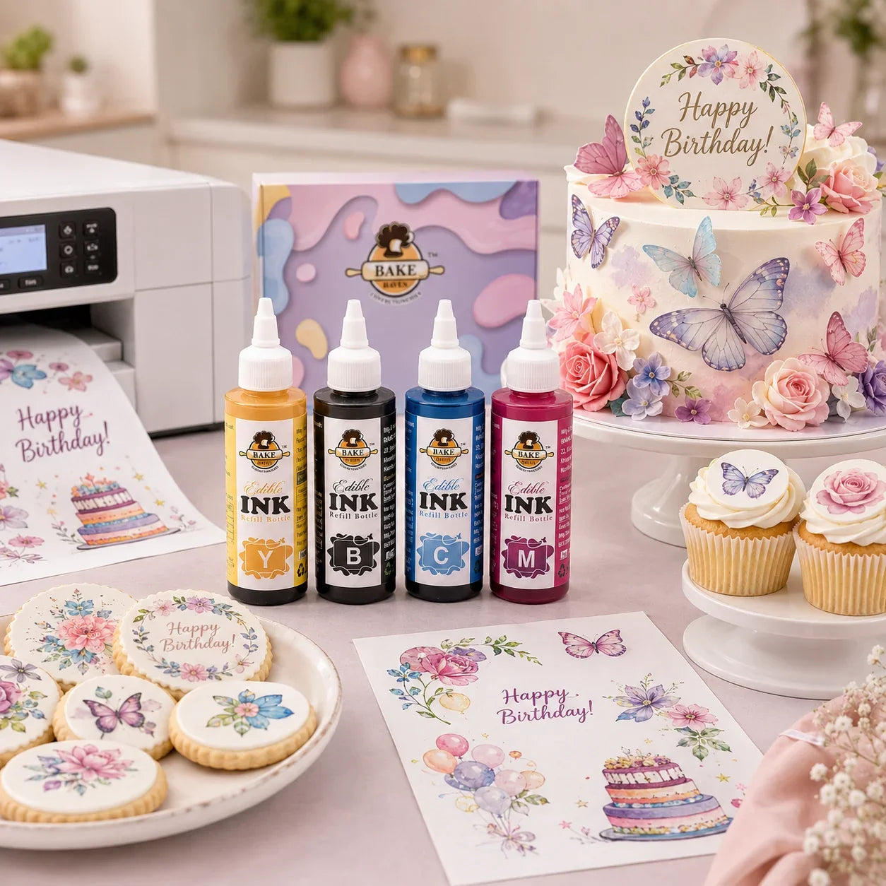 Edible ink bottles and printed items on a table with a decorated cake and cookies.