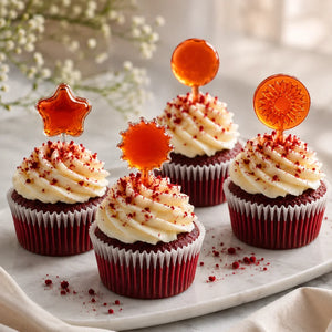 Red velvet cupcakes with cream cheese frosting and decorative toppers on a marble surface.
