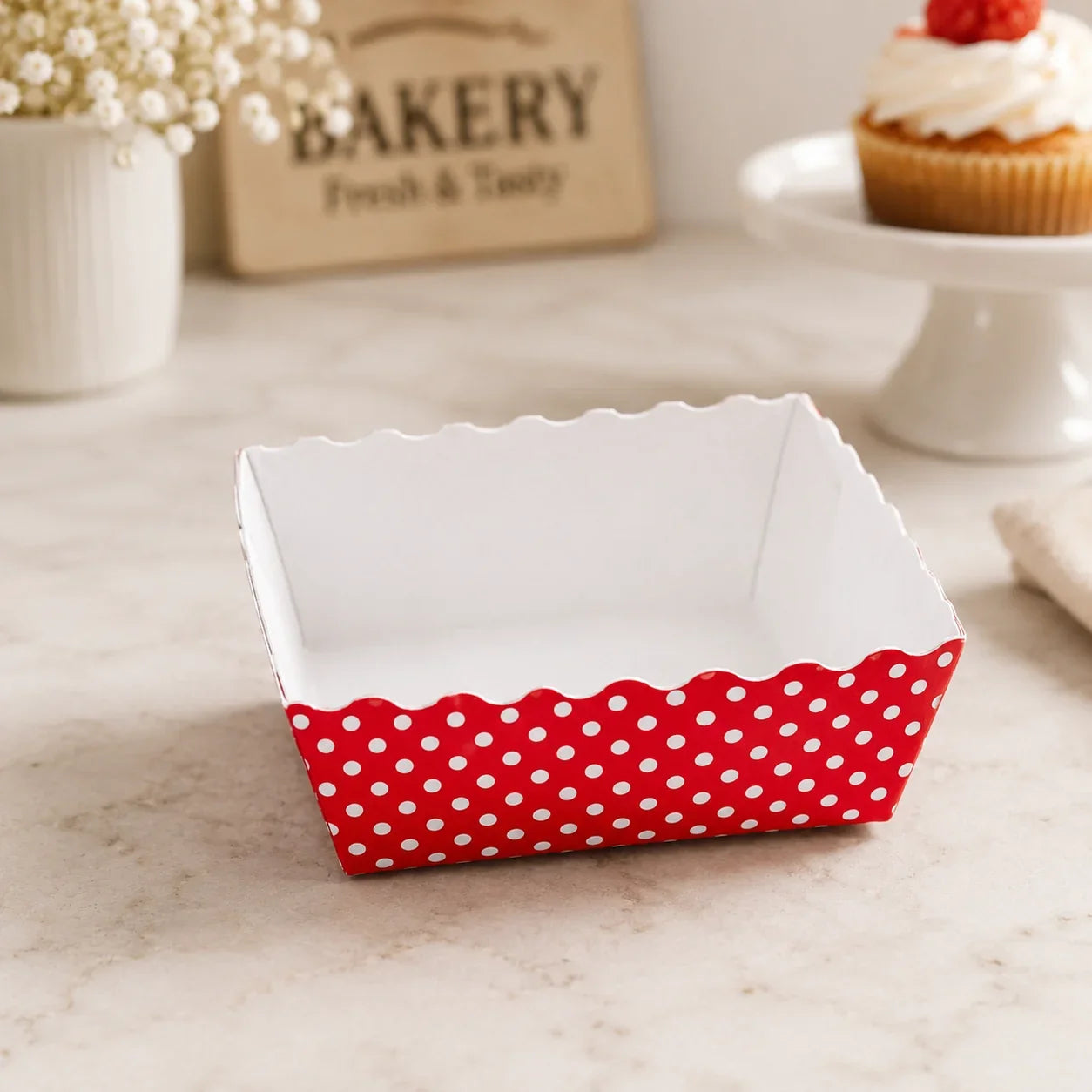Red and white polka dot paper basket on a marble surface with a bakery-themed background.