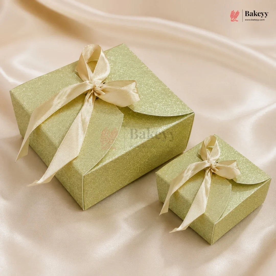 Two green gift boxes with ribbons on a beige fabric background, featuring the Bakey brand.