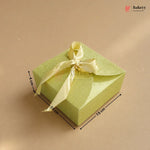Green gift box with a yellow ribbon and measurements on a beige background, featuring the Bakey brand.
