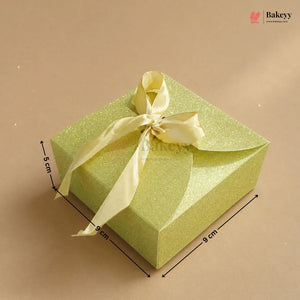 Green gift box with a yellow ribbon on a beige background, featuring dimensions.