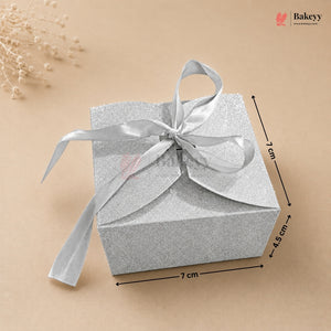 Silver gift box with a ribbon on a beige background, featuring dimensions.