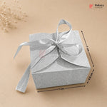 Silver gift box with a ribbon on a beige background, featuring dimensions.