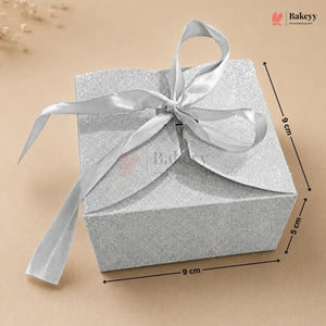 Silver gift box with a ribbon on a beige background, featuring the Bakey brand.
