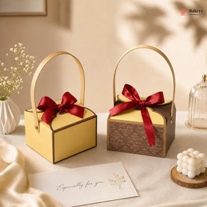 Two decorative boxes with red ribbons on a table with a card and small plant.