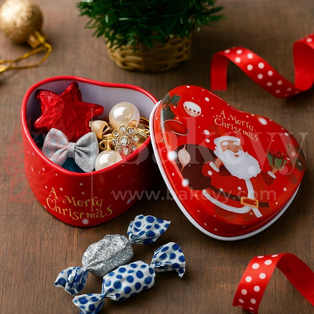 Heart-shaped Christmas tin with decorative items and candies on a wooden surface