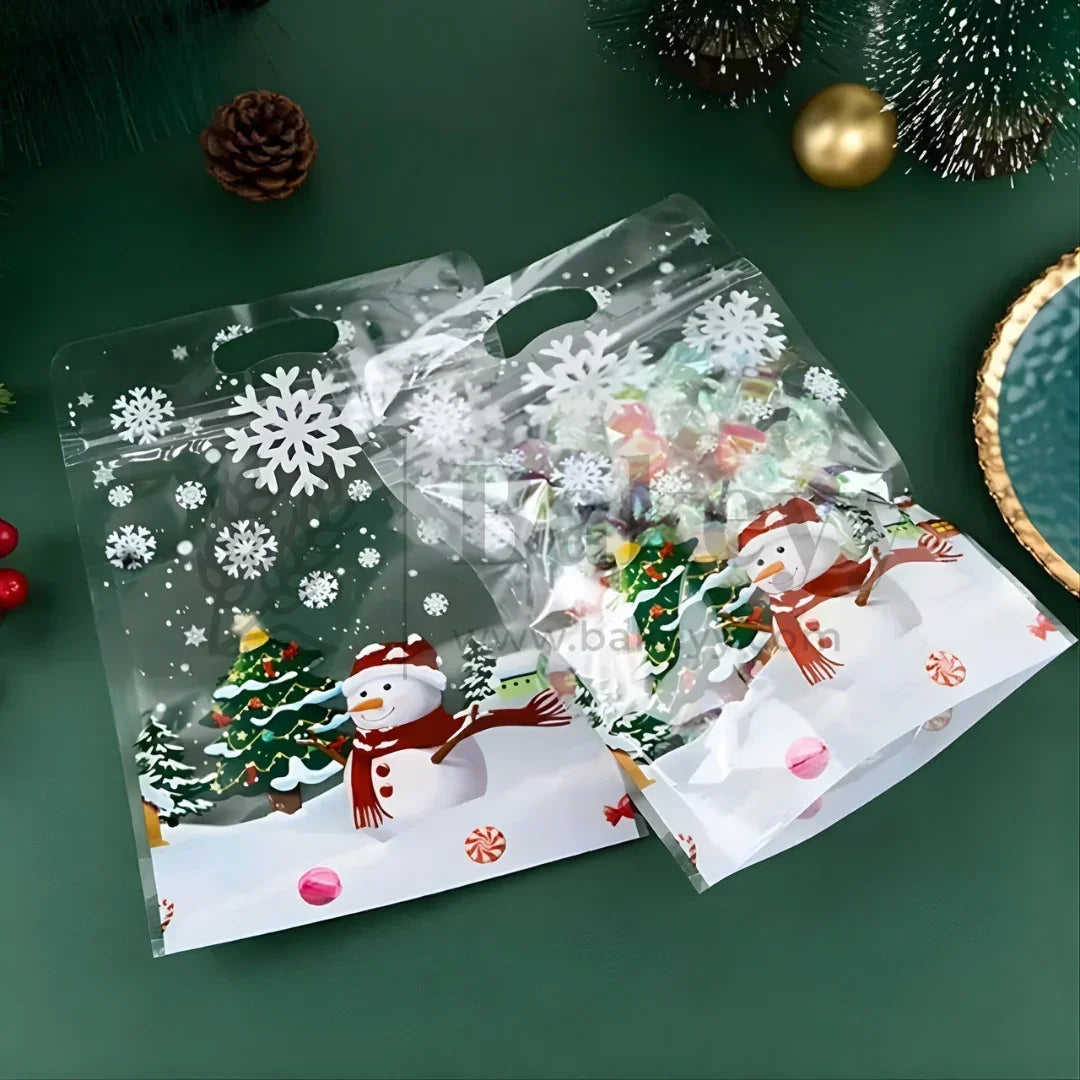 Clear cellophane bags with Christmas-themed designs on a green surface.
