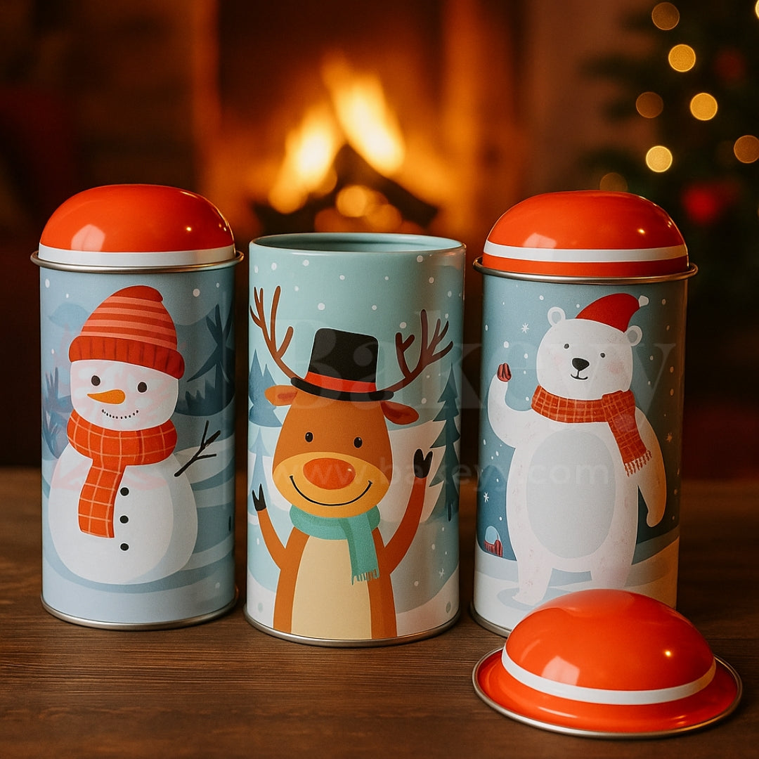 Three cylindrical containers with festive designs of a snowman, reindeer, and polar bear against a warm fireplace background.