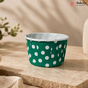 Green cupcake liner with white polka dots on a wooden surface, featuring the Bakey brand.