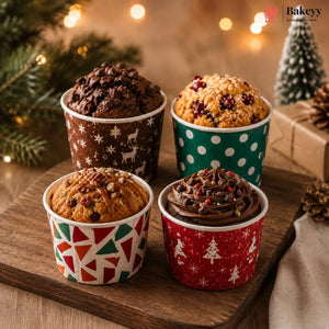 Four muffins in festive paper cups on a wooden board with Christmas decorations in the background.