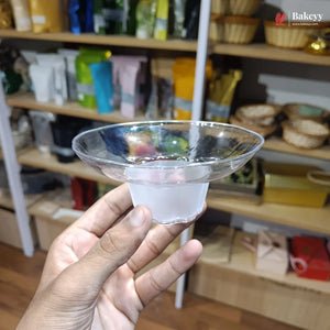 Hand holding a clear plastic funnel with shelves and products in the background