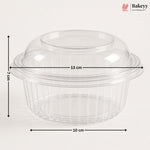 Clear plastic dome lid with a flared rim and ribbed base, shown with dimension arrows and labels indicating 13 cm width, 10 cm base diameter, and 7 cm height on a light gray background. Bakeyy logo appears in the top right.