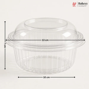 Clear plastic dome lid with a flared rim and ribbed base, shown with dimension arrows and labels indicating 13 cm width, 10 cm base diameter, and 7 cm height on a light gray background. Bakeyy logo appears in the top right.