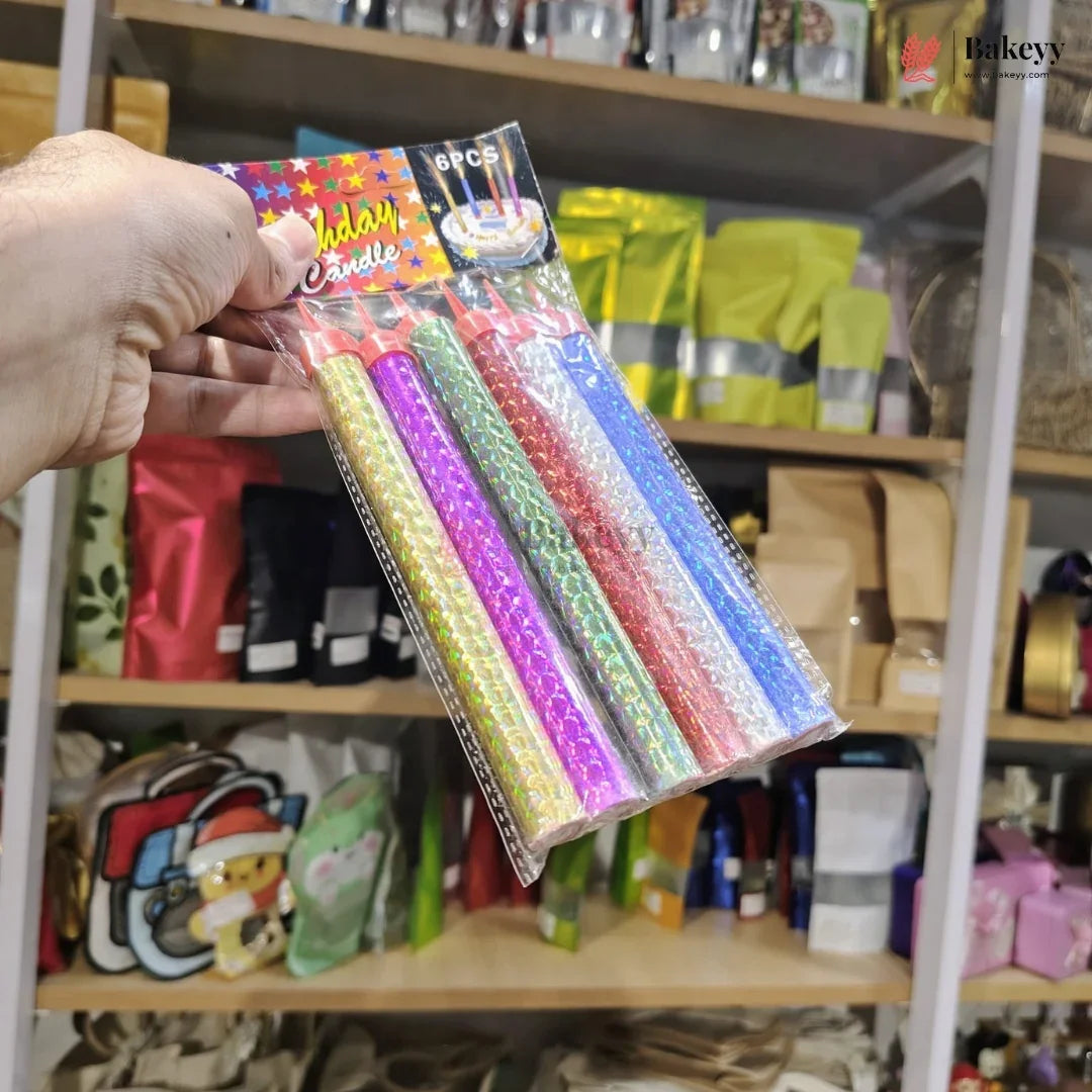 Hand holding a package of colorful candles with a store shelf in the background