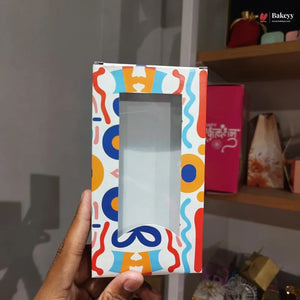 Colorful gift box with a clear window held by a hand against a blurred background