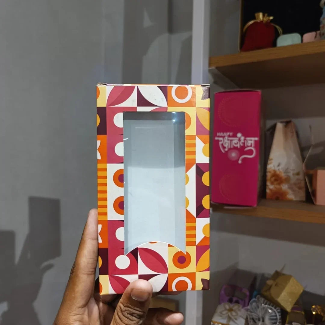 Colorful box with geometric pattern held by a hand against a blurred indoor background