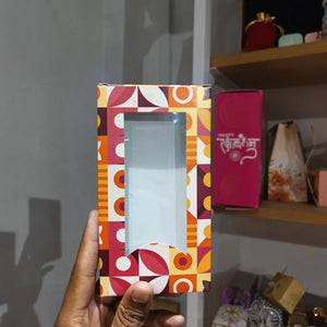 Colorful box with geometric pattern held by a hand against a blurred indoor background