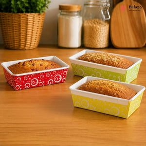 Three loaf pans with baked goods on a wooden surface, featuring colorful patterns.