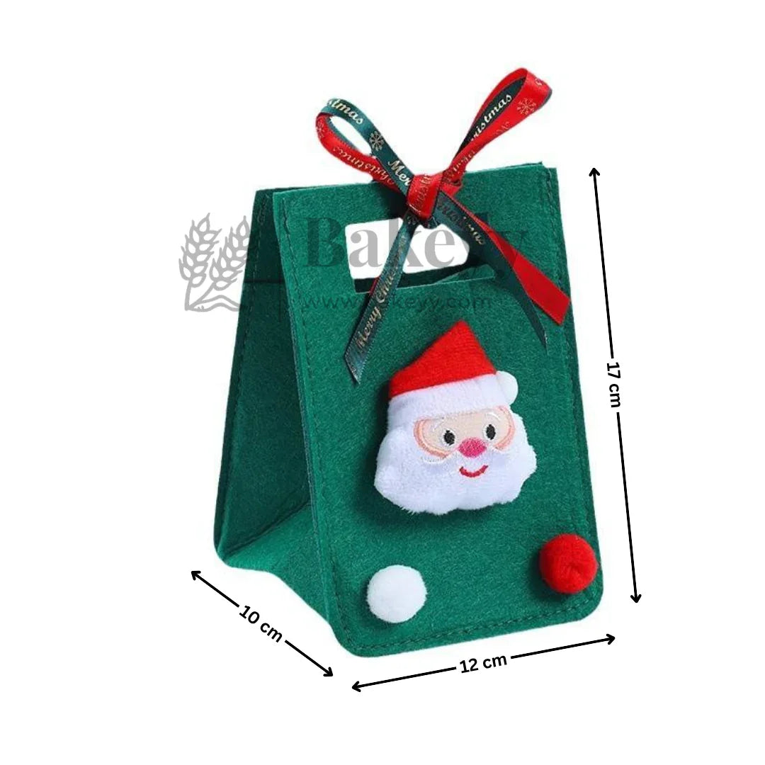 Green gift bag with Santa Claus face design and red ribbon, dimensions indicated.