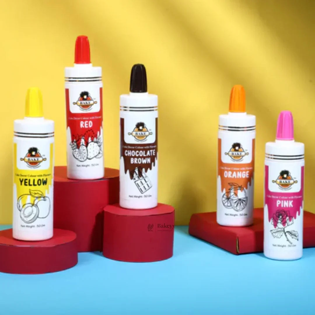 Five Bakeyy cake flavour and color bottles—yellow, red, chocolate brown, orange, pink—on colorful display