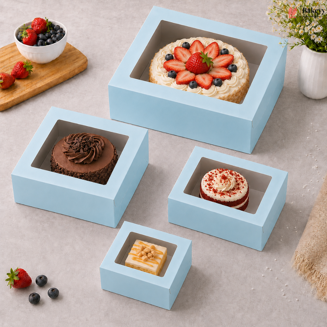 Four light blue cake boxes with transparent windows displaying various desserts on a gray surface.