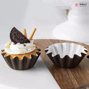 Chocolate cupcake with whipped cream and an Oreo cookie next to a chocolate mold on a wooden board.