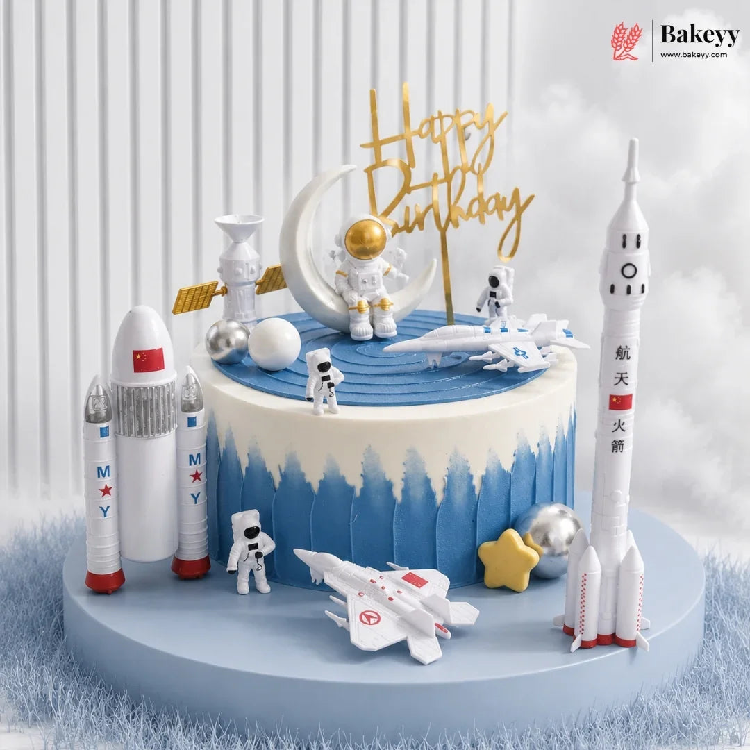 Space-themed birthday cake with rockets, astronauts, and a 'Happy Birthday' sign on a white background.