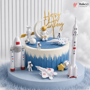 Space-themed birthday cake with rockets, astronauts, and a 'Happy Birthday' sign on a white background.